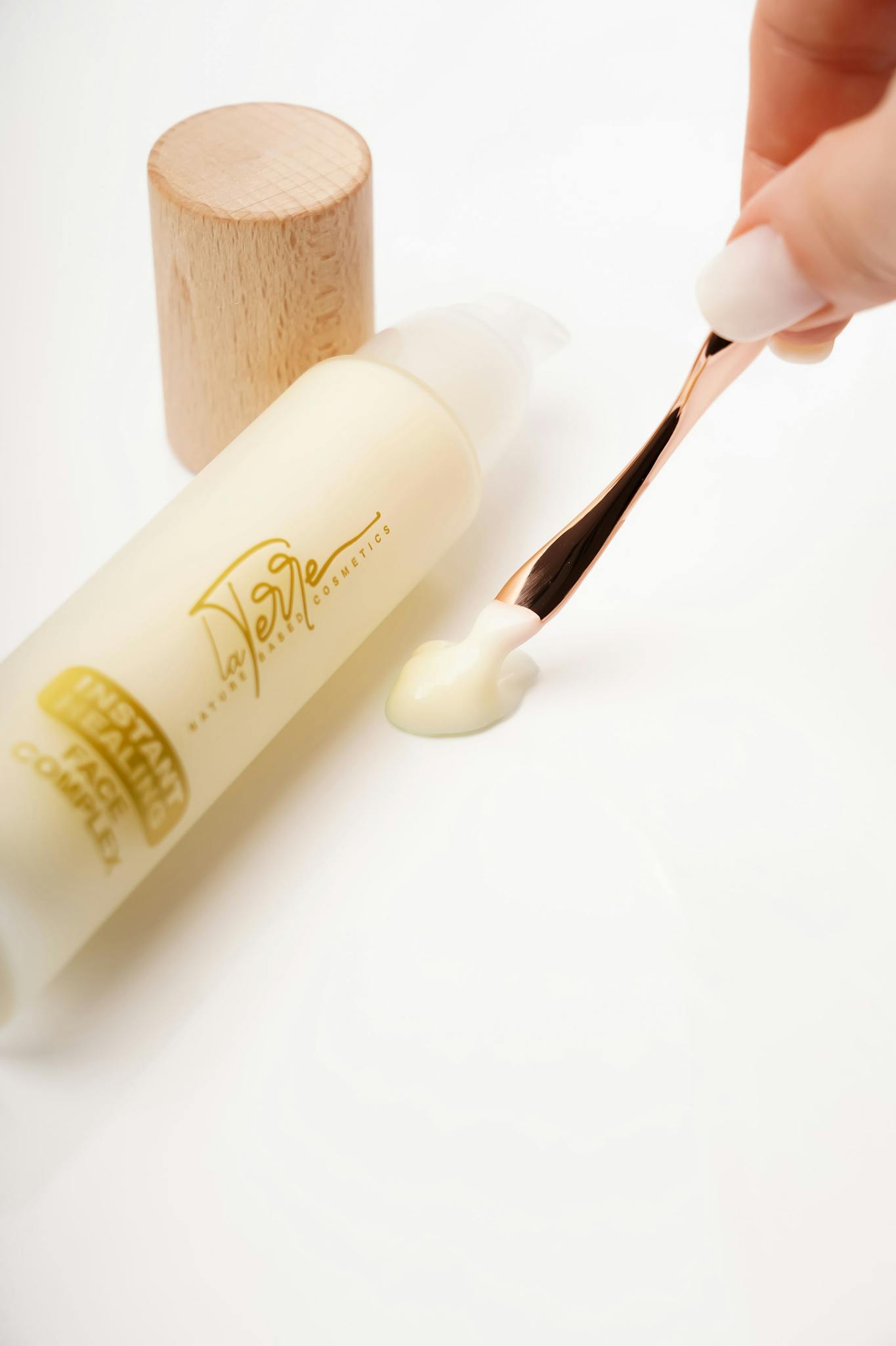 High-end skincare product with wooden cap and elegant scoop on white background.